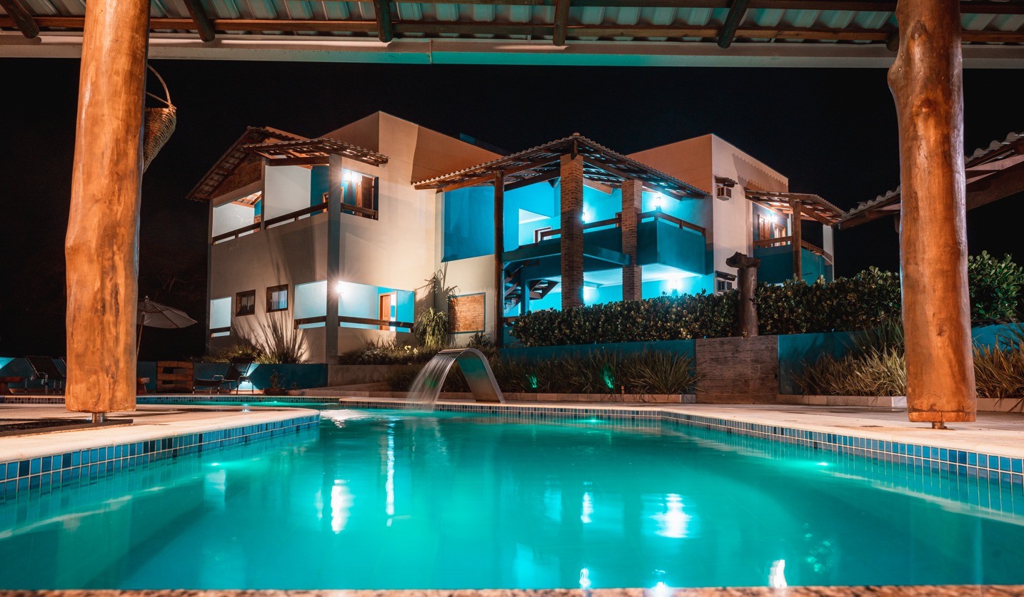 Área externa da Pousada do Painho à noite com piscina iluminada